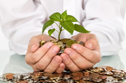 Businessman holding plant sprouting from a handful of coins - good investment and money concept