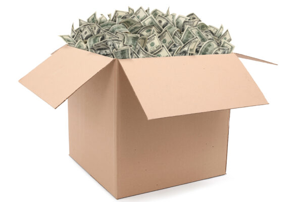 Cardboard box overflowing with money (one hundred-dollar bills). Isolated on white background.